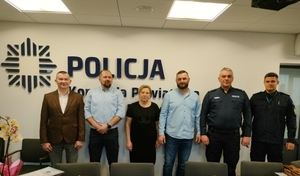 Na zdjęciu trzech policjantów odchodzących na emeryturę i pracownik cywilny. Zdjęcie pamiątkowe razem z Komendantem oraz Naczelnikiem na tle napisu Komenda Powiatowa Policji w Pińczowie.